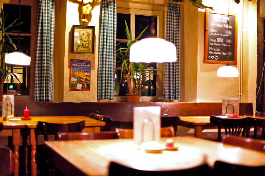 Grüne Gans Urige Kneipe Osnabrück Innenansicht eines Restaurants mit Tischen, Stühlen, Lampen und Dekoration. Gruene Gans.